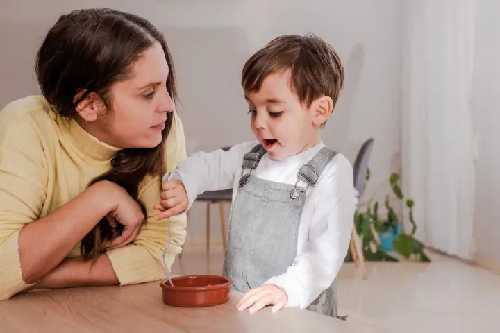 Mama uważnie słucha, jak dziecko opowiada o swojej zabawie. To przykład, jak rozmawiać z dzieckiem, budując więź i zrozumienie.