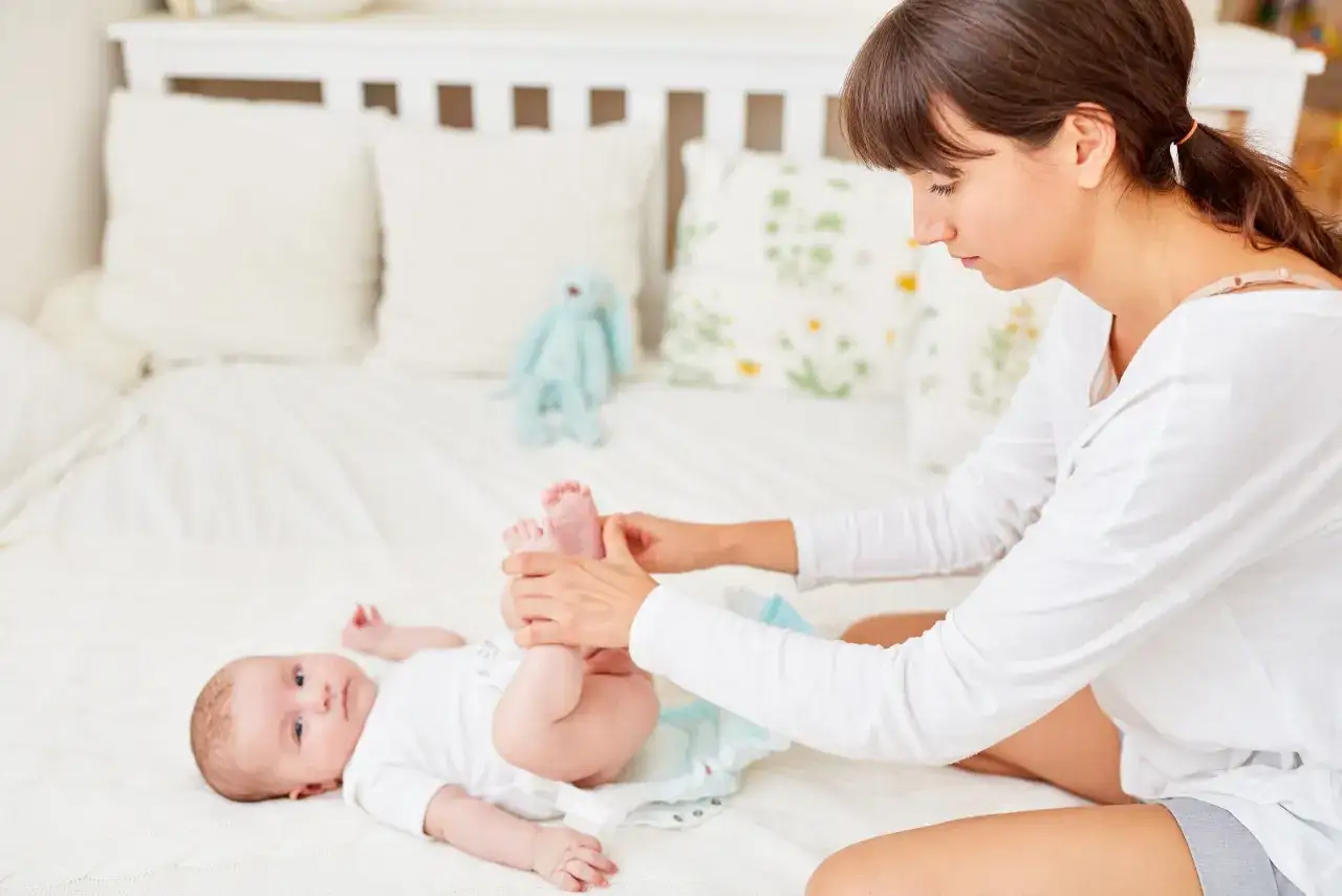 Mama zmienia pieluchę noworodkowi. Wybór odpowiednich pieluch dla maluszka to ważna decyzja.