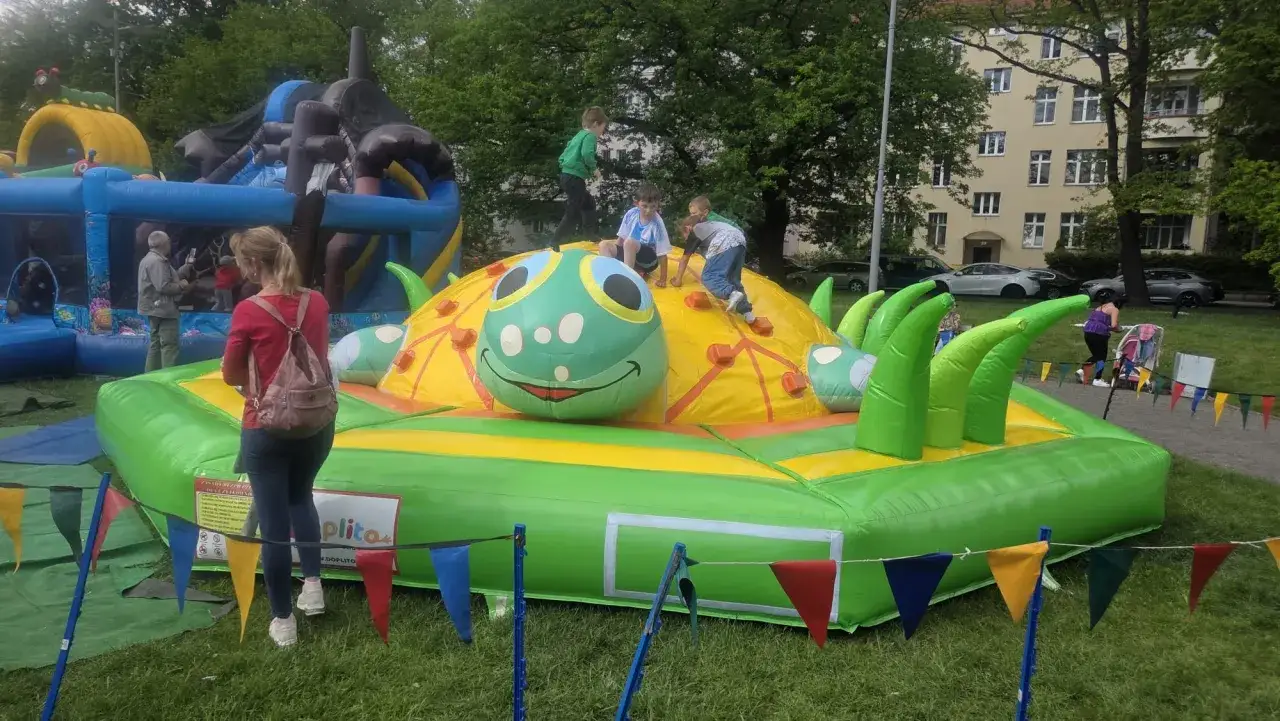 Radosne dzieci bawią się na dmuchanej zjeżdżalni w kształcie gąsienicy, gdy jest dzień dziecka.